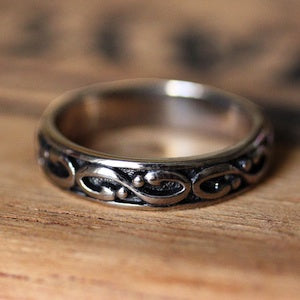Men's white gold wedding band with infinity detailing and black enamel.