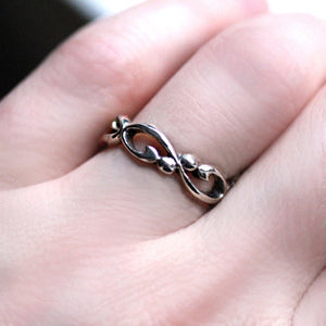 Silver infinity filigree band being worn on a woman's hand