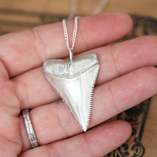 Sterling silver great white shark tooth from Metalicious resting on a hand