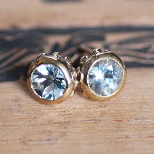 14k Gold stud earrings with blue aquamarine gemstones and unique detailing.